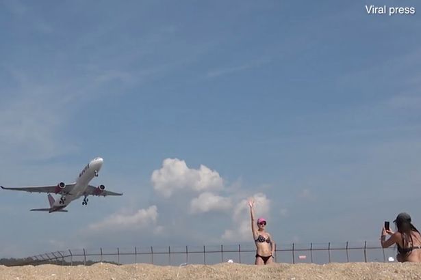 السياح يلتقطون الصور مع صعود الطائرات من المطار القريب من الشاطئ فى تايلاند